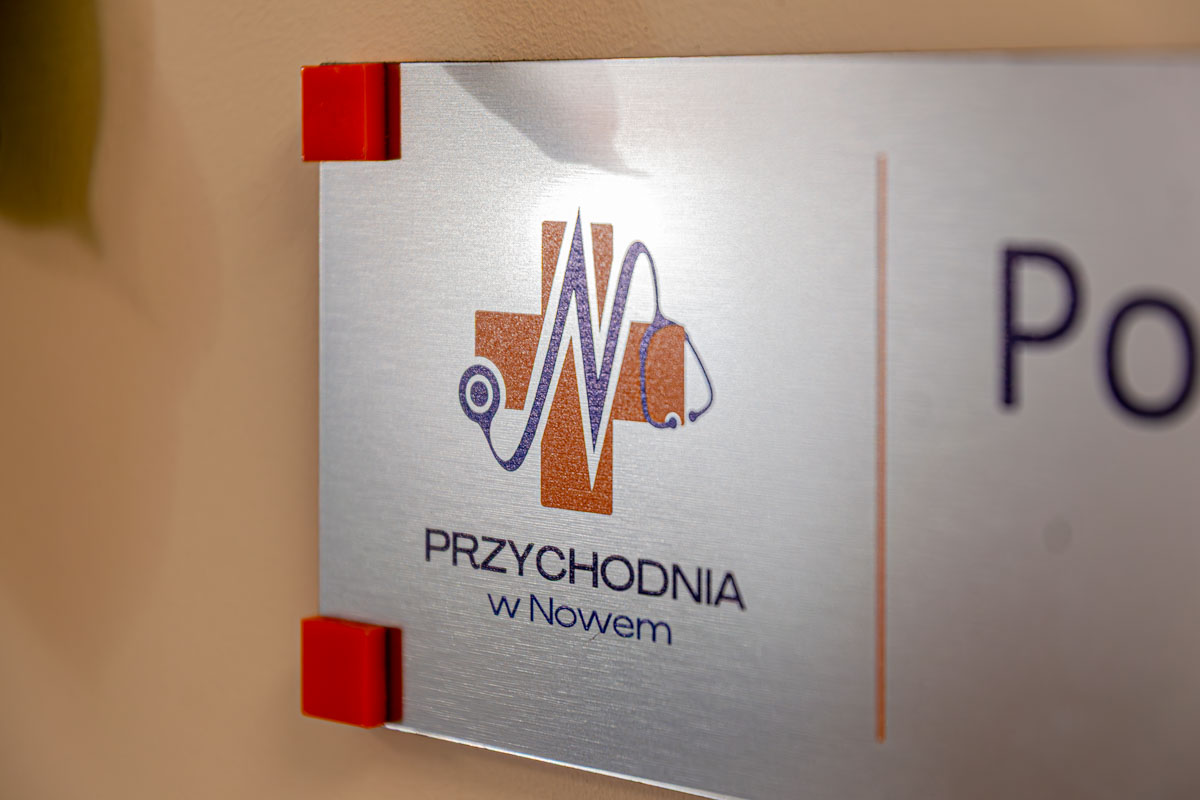 Tabliczka z logo i napisem „Przychodnia w Nowem” zamontowana na ścianie.