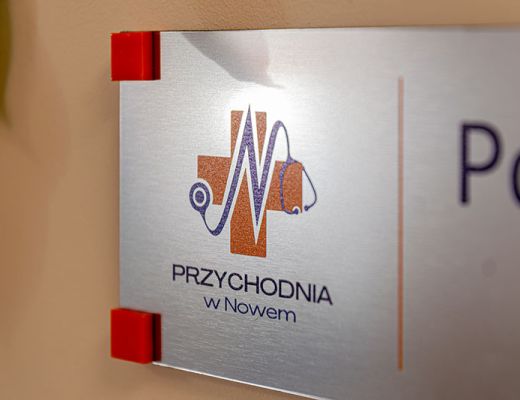 Tablica z logo Przychodni w Nowem zamontowana na ścianie.